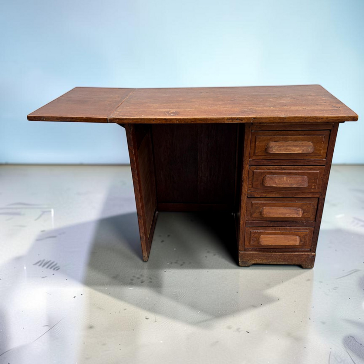 Bureau vintage NewUsed Collection en bois avec quatre tiroirs et une allonge latérale sur fond bleu clair